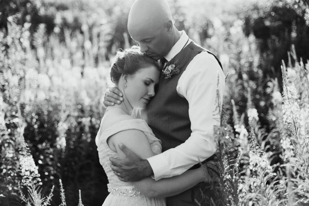 bride and groom embrace in tall wildflowers during Gros Morne elopement