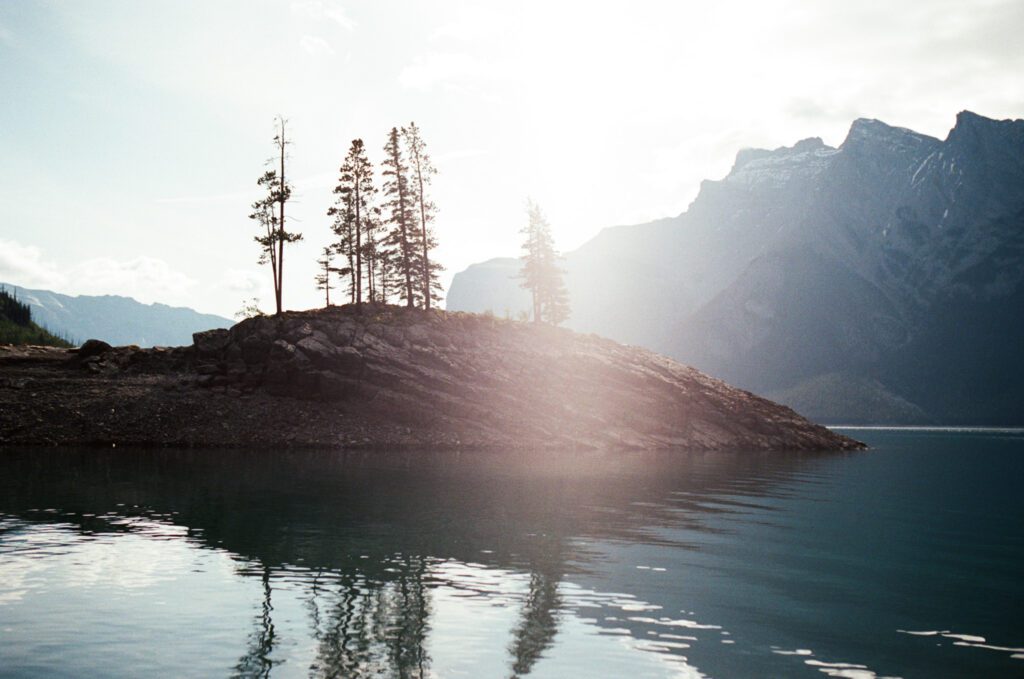 35 mm film photo of the sun rising over Lake Minnewanka in Banff with mountains in the background