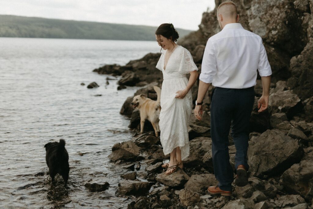 bride and groom explore the beach with their two dogs during their elopement