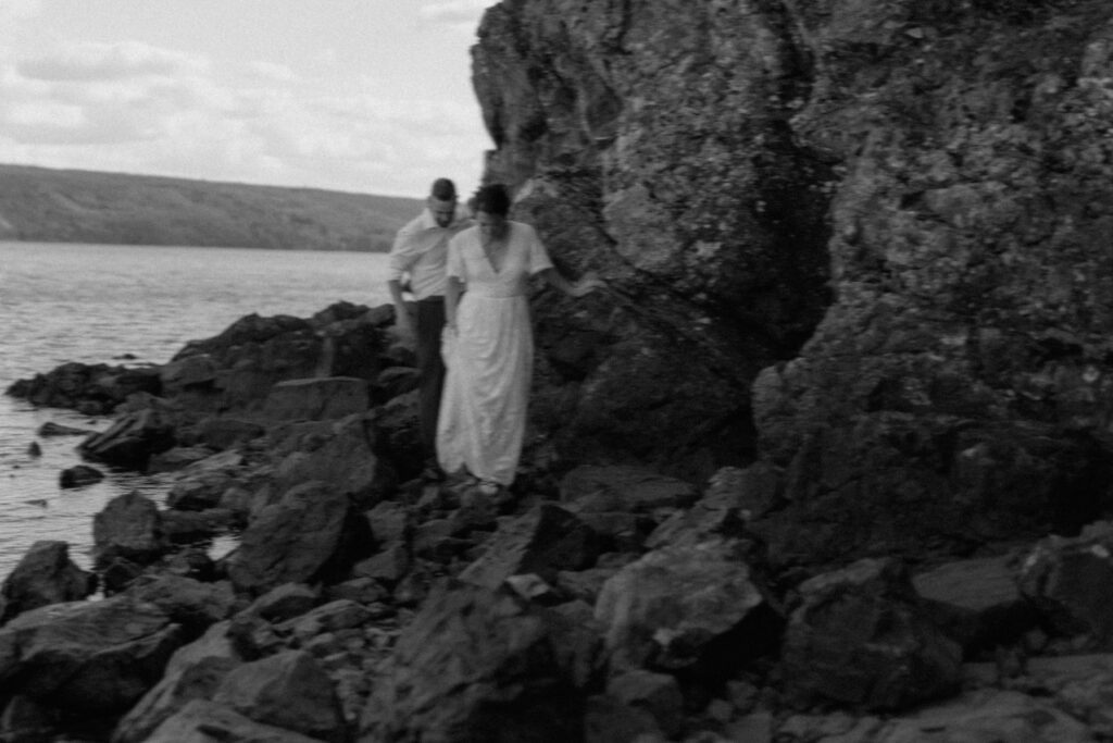 bride and groom explore the rocky shore during their elopement