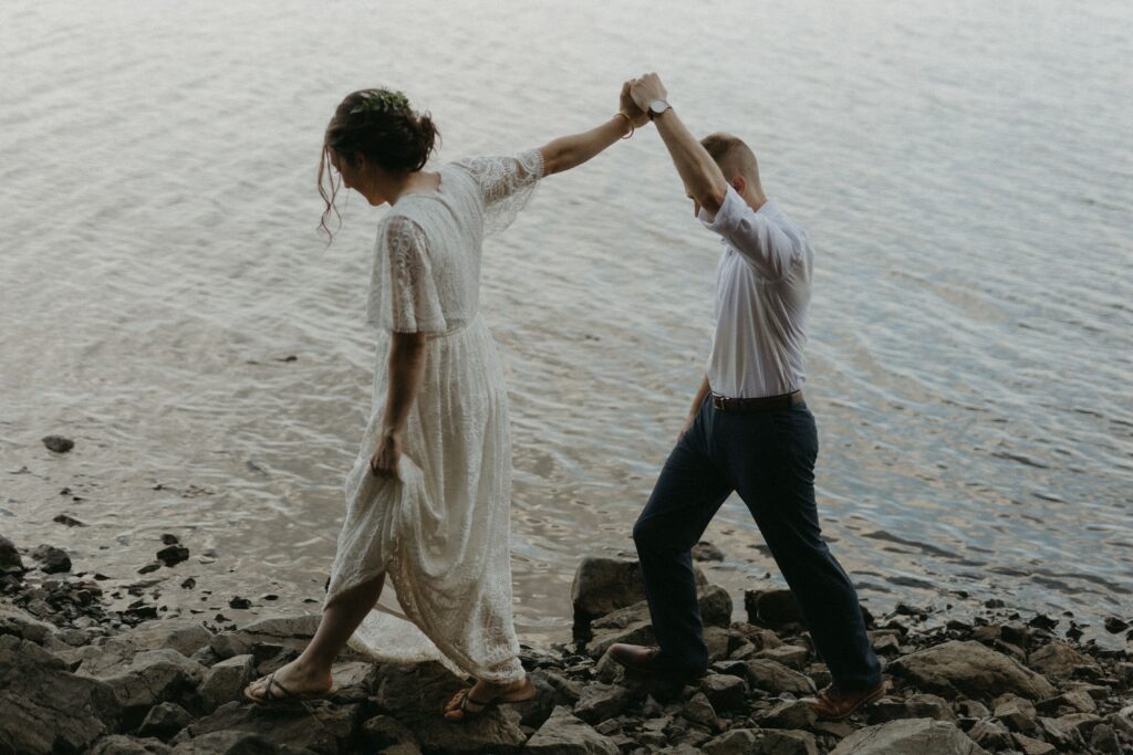 bride and groom explore the rocky shore during their elopement
