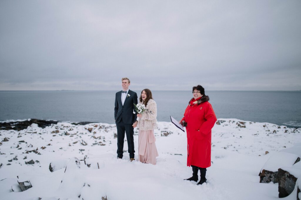 bride and groom laugh during elopement ceremony on snowy Fogo Island