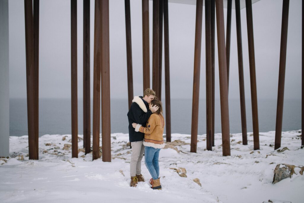 groom kisses the bride's head as they cuddle beside the Fogo Island Inn.