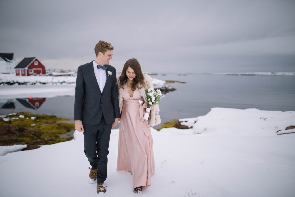 bride and groom walk through a snowy barren landscape on Fogo Island