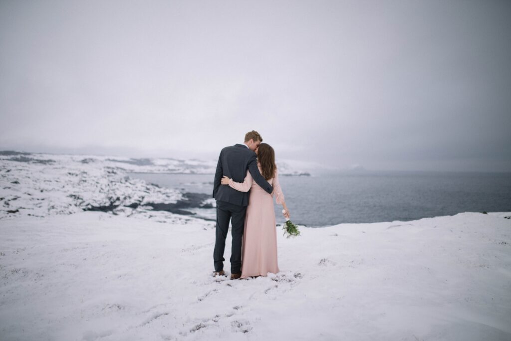 bride and groom kiss in a snowy barren landscape on Fogo Island