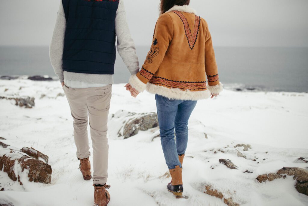 Bride and Groom hold hands and explore the snowy landscape around the Fogo Island Inn.