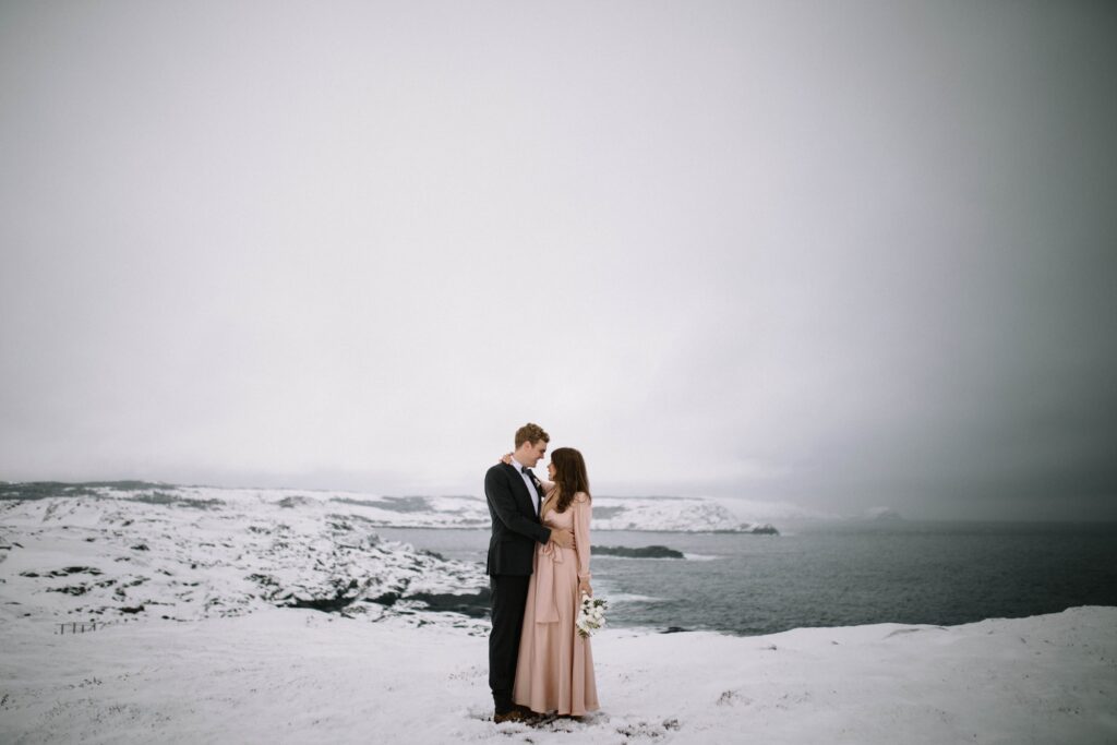 bride and groom hold each other in a snowy barren landscape