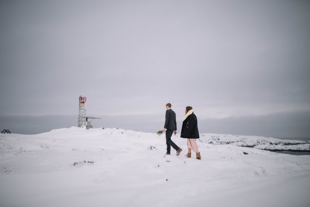 bride and groom walk through a snowy barren landscape