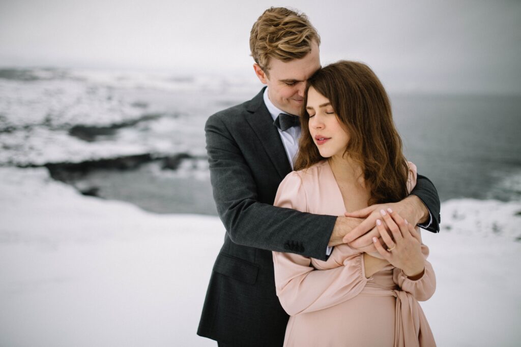 groom holds bride in a snowy barren landscape on Fogo Island