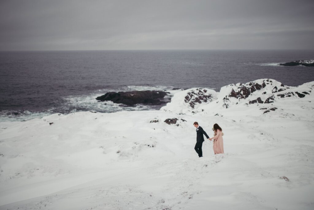 groom leads bride through a snowy Newfoundland landscape