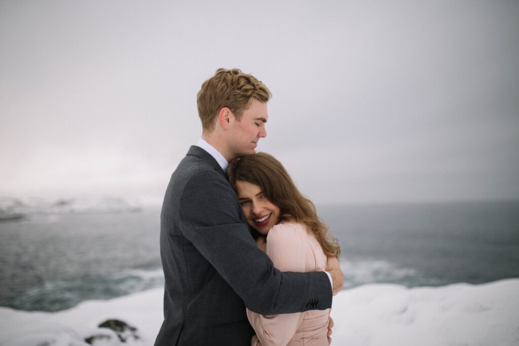 bride and groom cuddle in a snowy landscape.