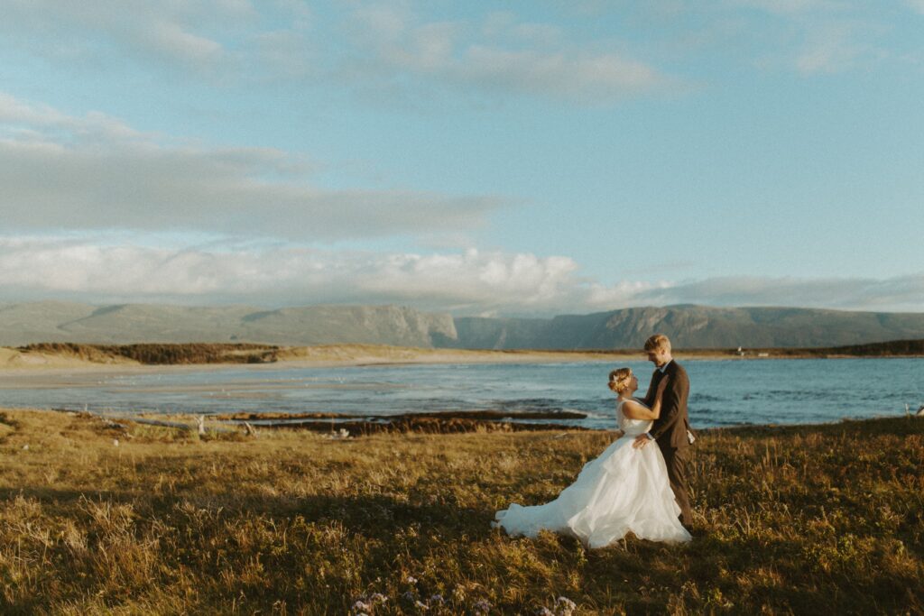 bride and groom embrace with the West Brook Pond fjord in the background in Gros Morne National Park