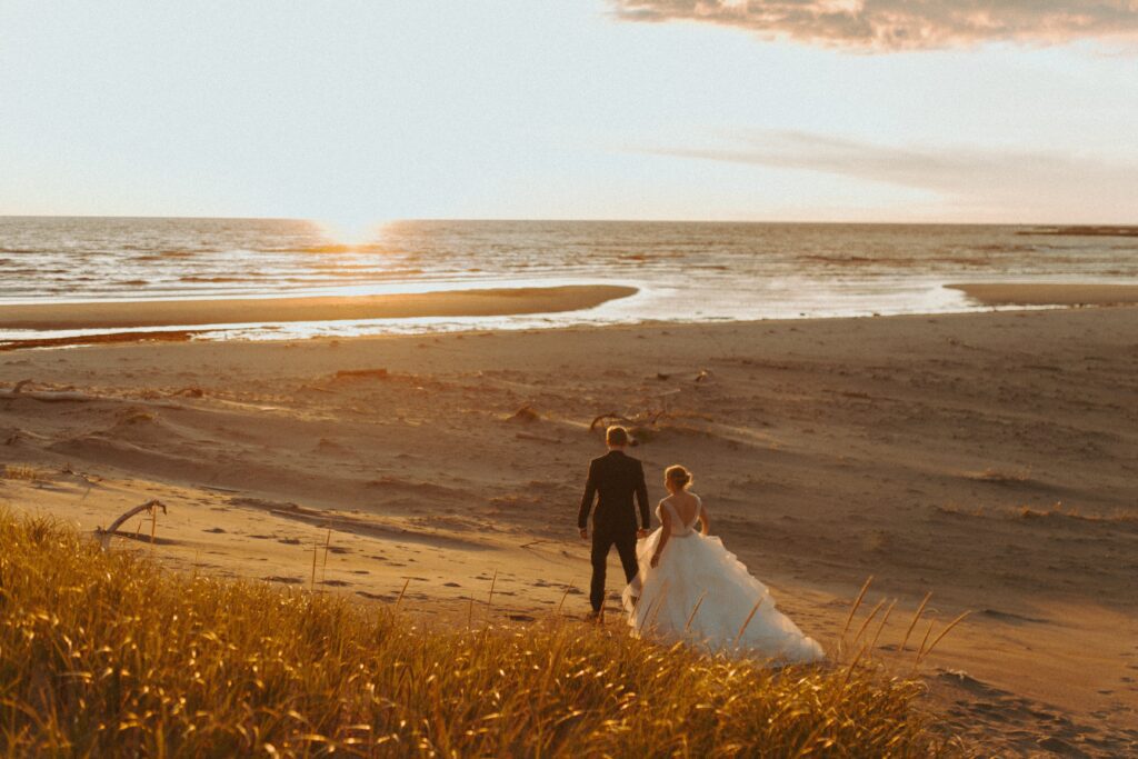 bride and groom explore sandy beach at sunset in Gros Morne National Park