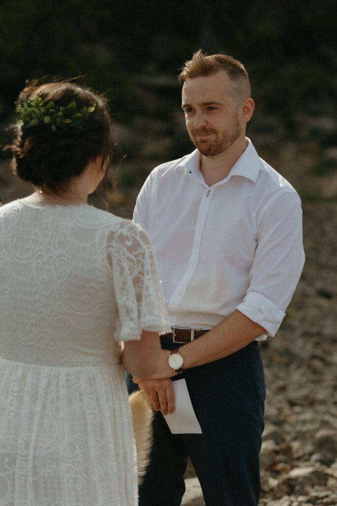 groom smiles at bride as she reads vows during Newfoundland elopement ceremony