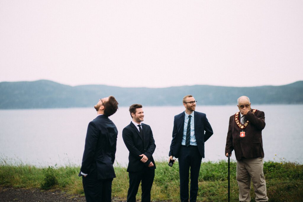 groomsmen grin as groom waits to turn around at Newfoundland wedding ceremony