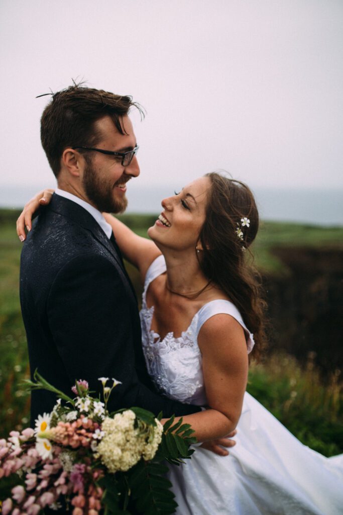 bride and groom laugh and embrace in the rain during their Newfoundland elopement