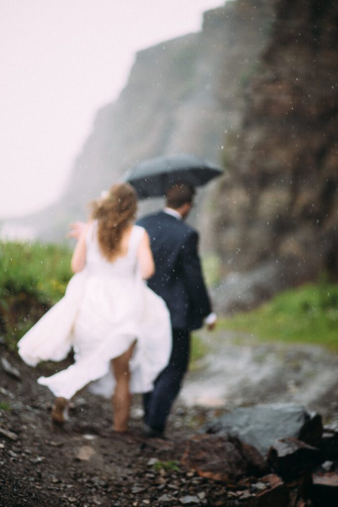 bride and groom walk through the pouring rain