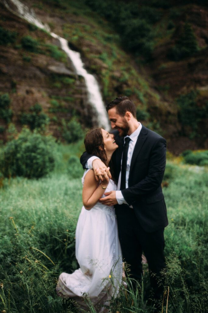 bride and groom grin at each other by a waterfall during their Newfoundland elopement