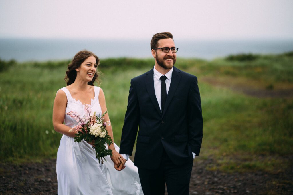 bride reaches for groom's hand at Newfoundland elopement ceremony