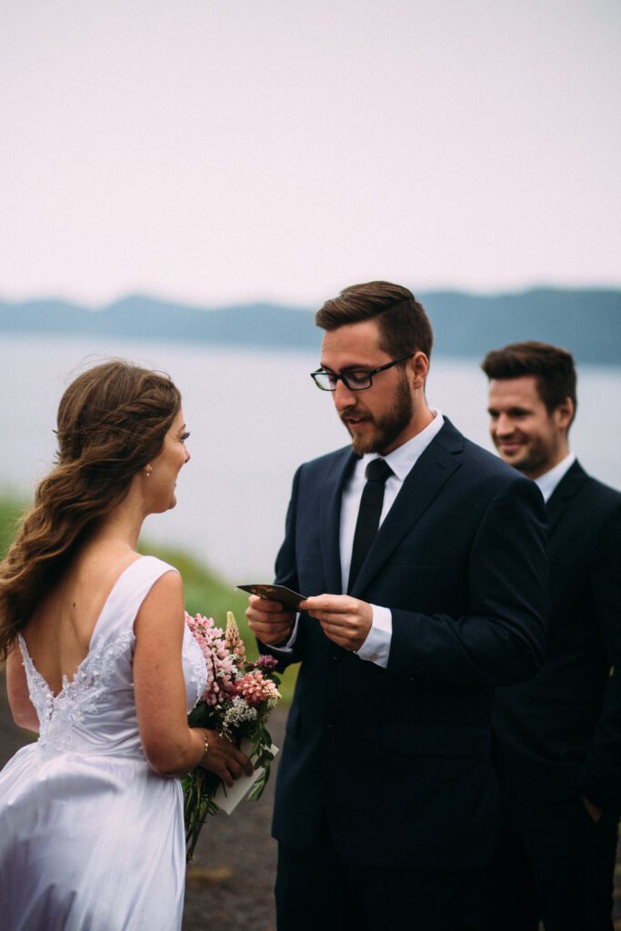 groom reads vows during elopement ceremony on the coast