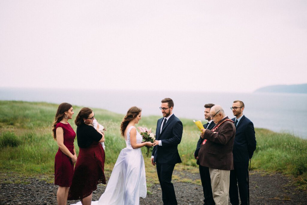 bride and groom exchange rings at intimate wedding ceremony on a clifftop