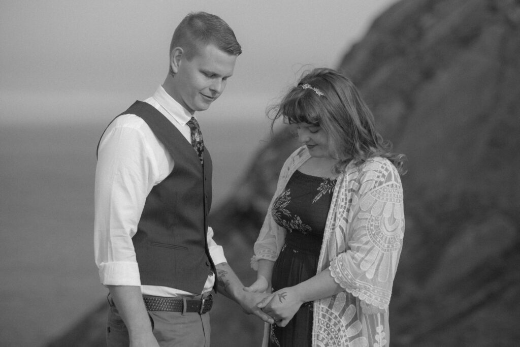 bride takes the groom's hand during elopement ceremony beside a cliff in Newfoundland