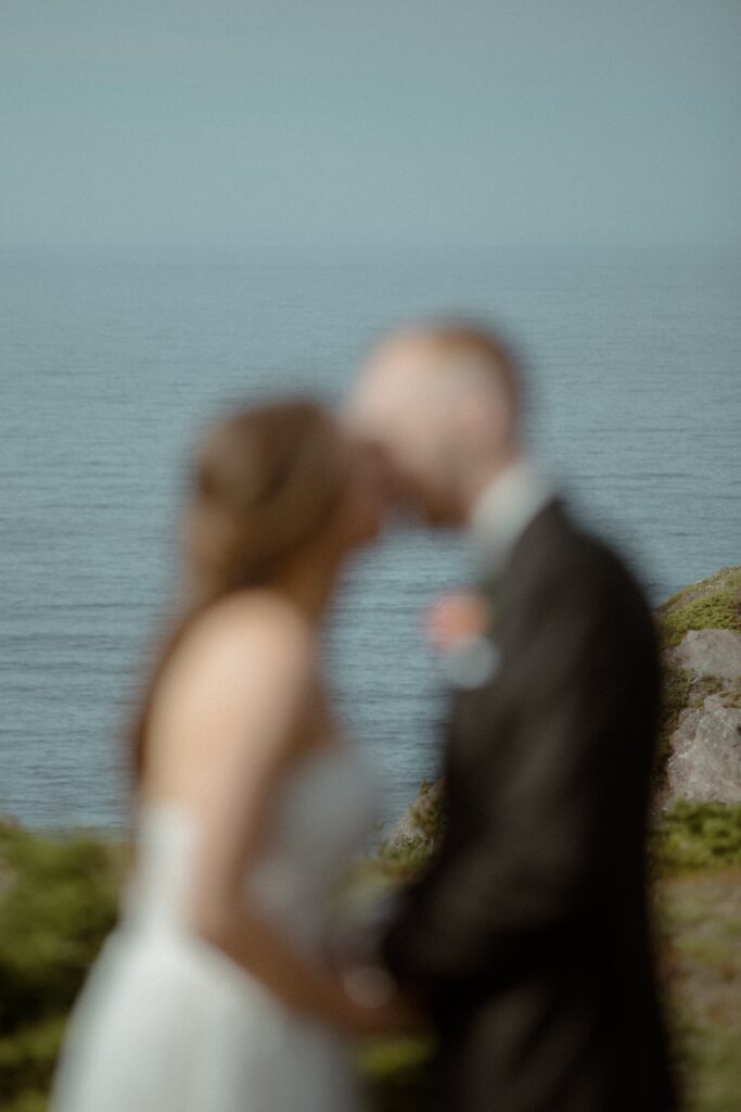 bride and groom kiss on. cliff above the ocean