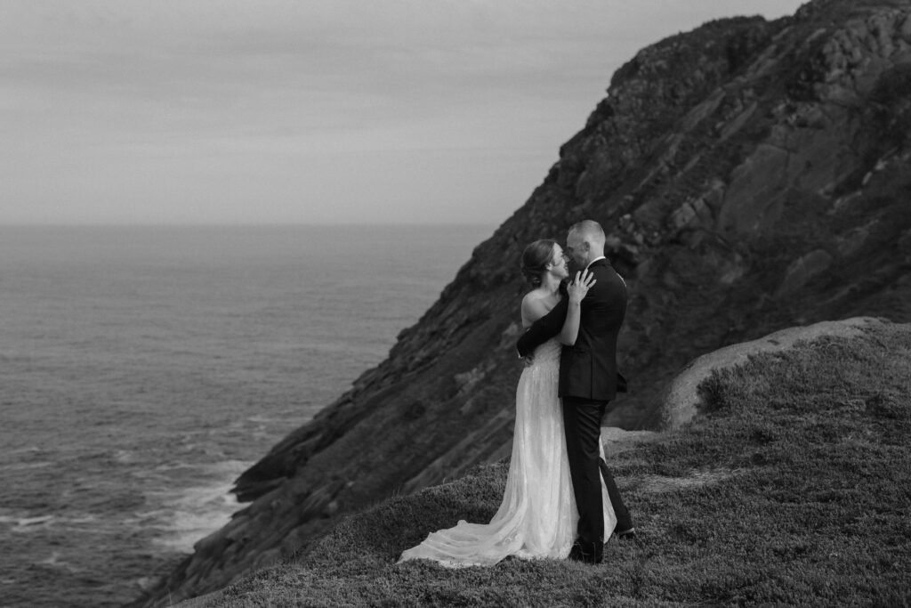 bride and groom embrace with an enormous sea cliff in the background during Newfoundland elopement