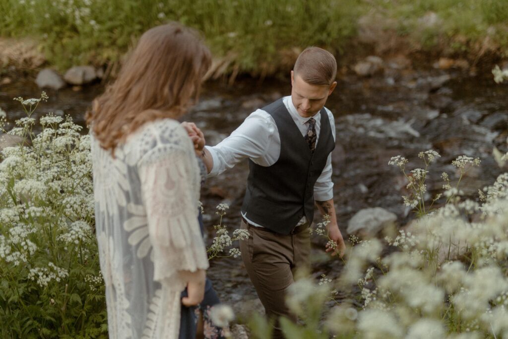 groom leads bride to a river during Newfoundland elopement