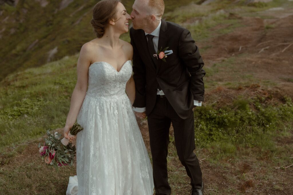 bride laughs as groom kisses her nose during Newfoundland hiking elopement