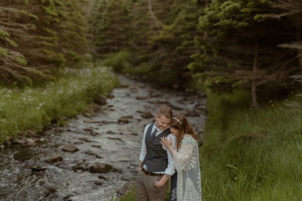 bride and groom hold each other by a river during Newfoundland elopement