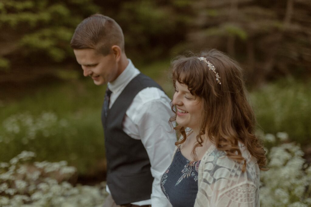 bride and groom laugh in a field of wildflowers