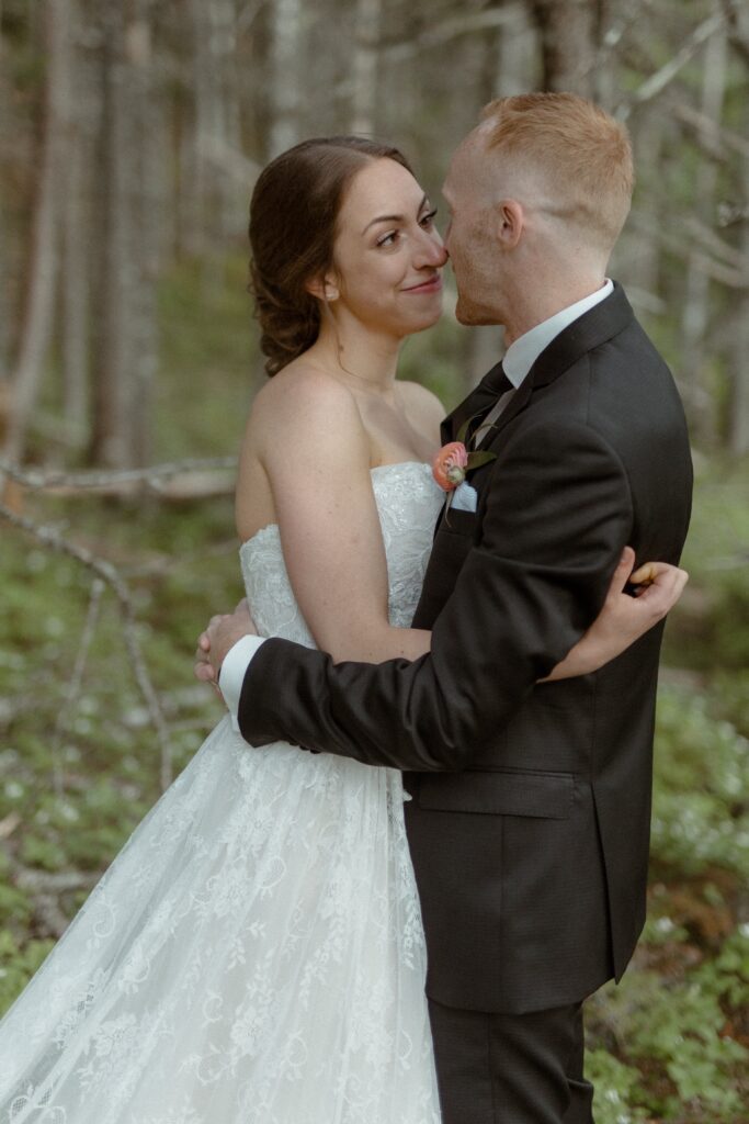 bride and groom look at each other with emotion in the forest during Newfoundland elopement