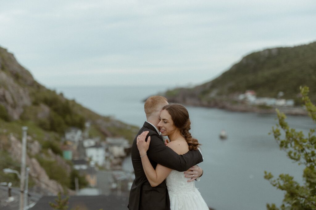 bride and groom hold each other at St. John's harbour during their elopement