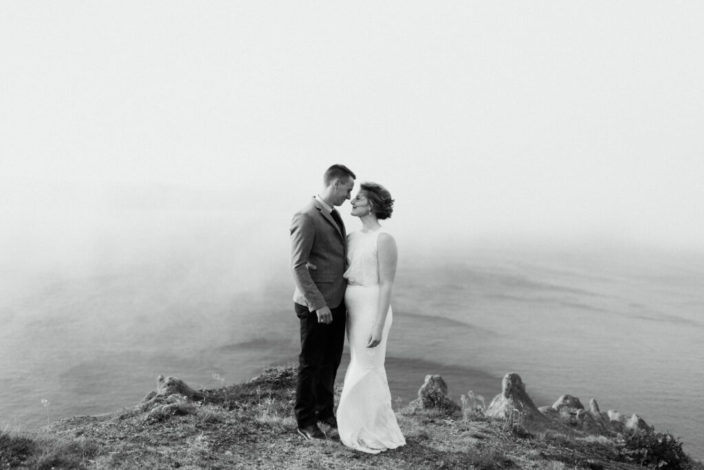 bride and groom hold each other on a rocky ledge in the fog during their Newfoundland elopement