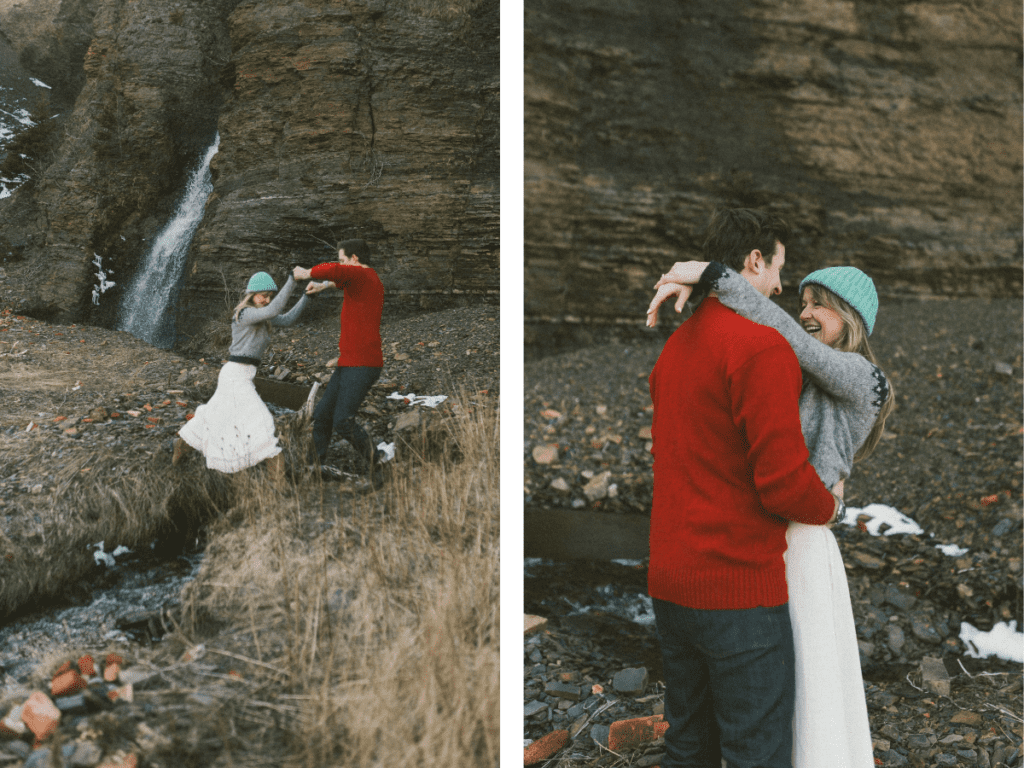couple in wool sweaters laugh in front of cliff