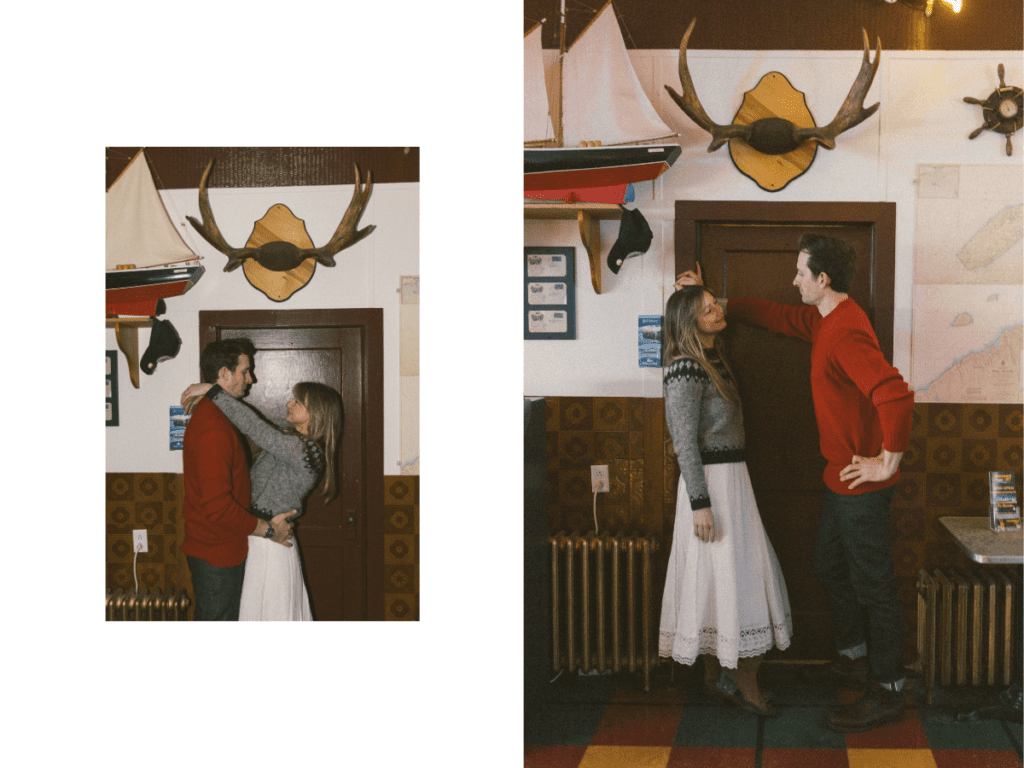 couple stand in doorway of dive bar surrounded by antlers, model ships, and maps