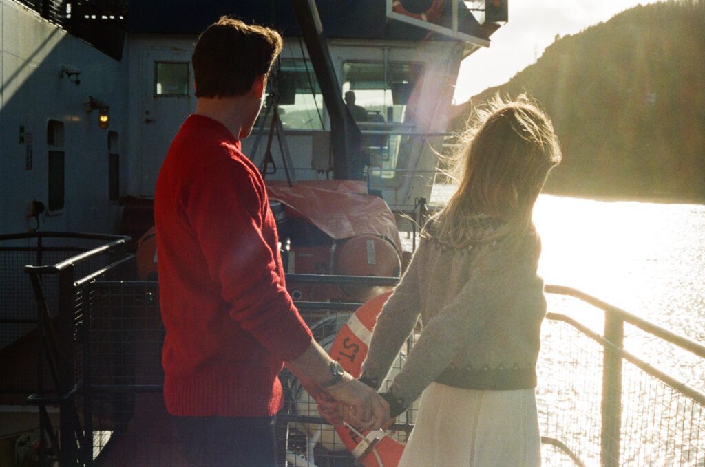 couple hold hands on a ferry in the sun