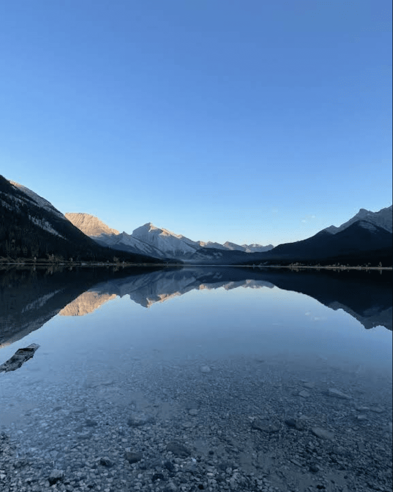 sunrise over the mountains with a still blue lake in the foreground at Spray Lakes Reservoir, Kananaskis