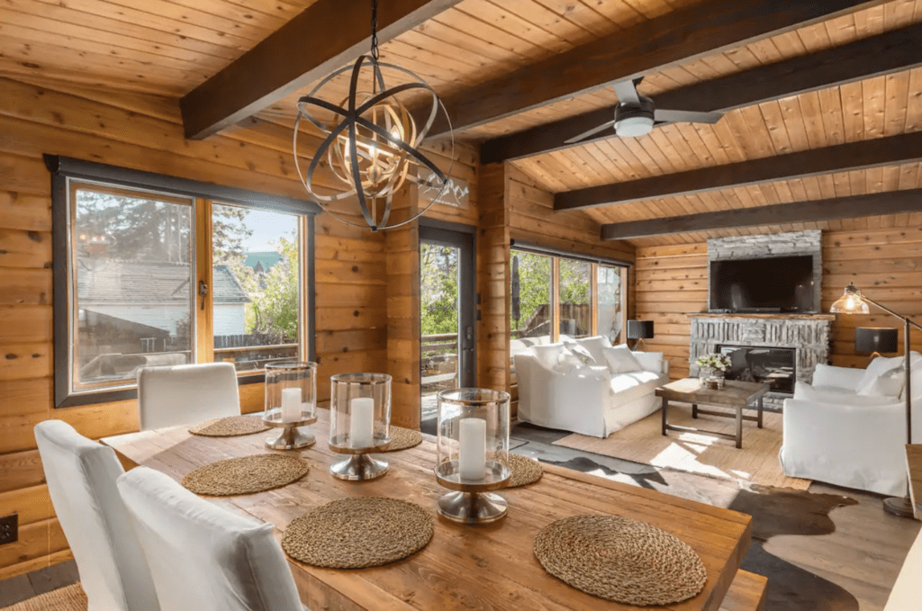 a modern rustic condo in Banff with a wooden table, white couches, pine walls, and sun coming in the large windows
