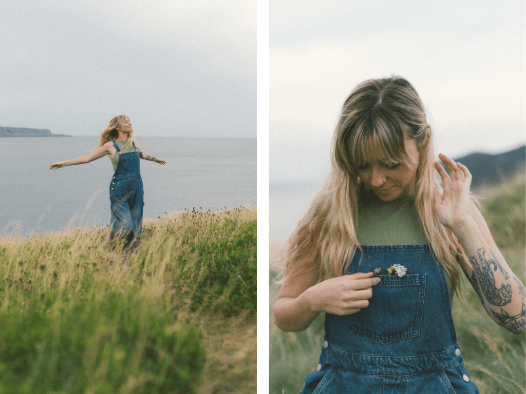 blonde woman with tattoos spins around in a meadow by the ocean during Self Love Session