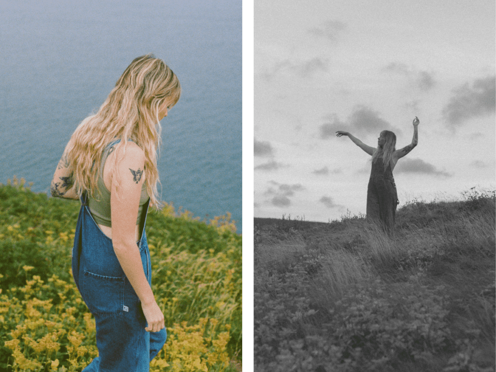 blonde woman with tattoos walks through a field of yellow wildflowers by the ocean