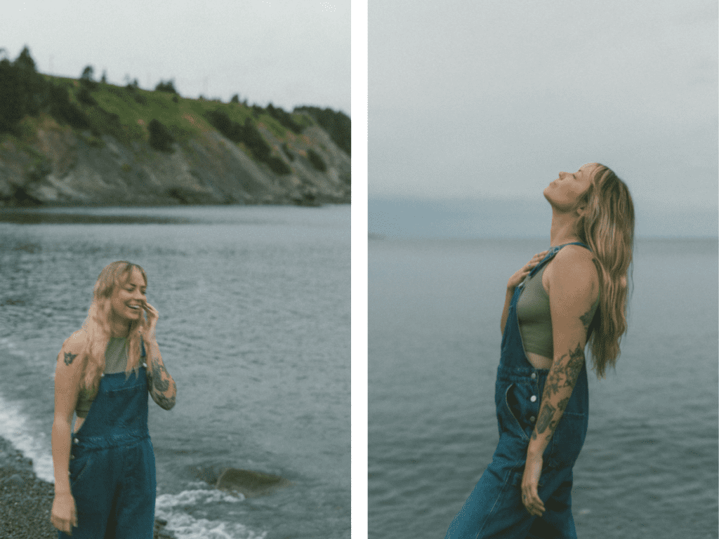 blonde woman with tattoos laughs on the sea shore at sunset