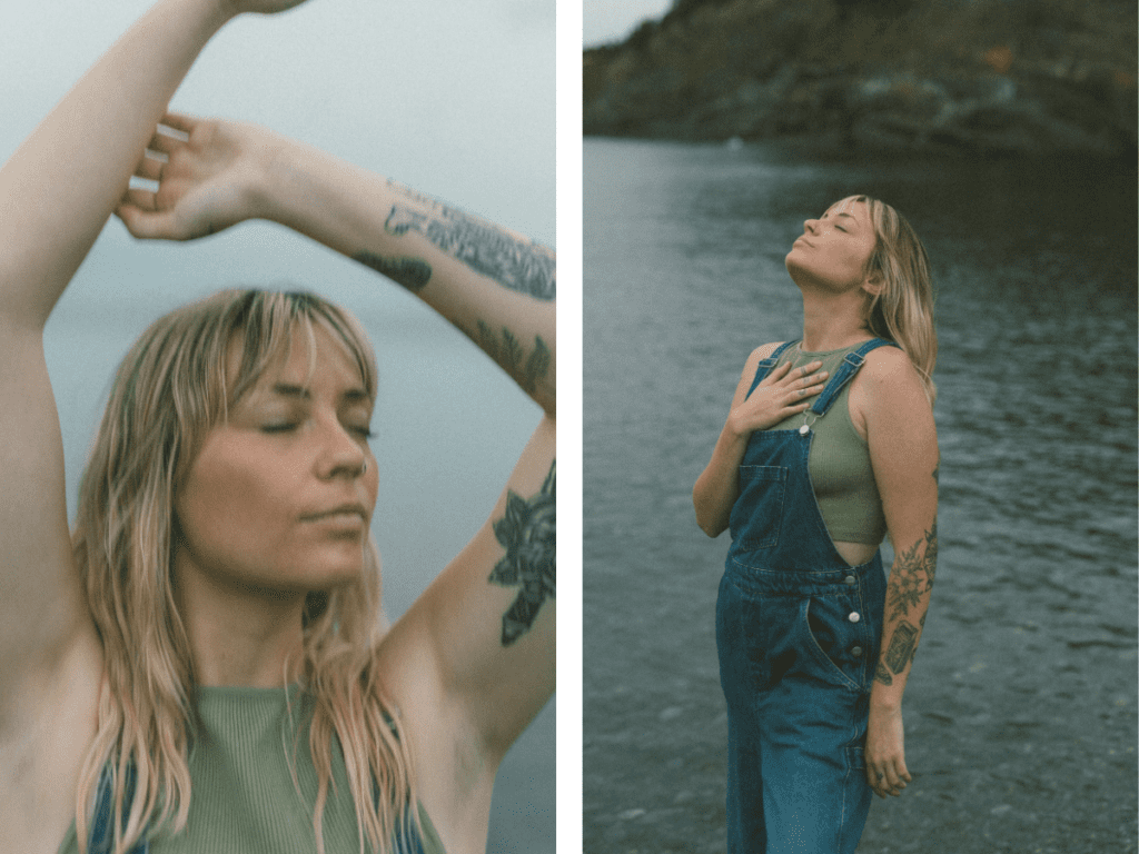 blonde woman with tattoos stands in a yoga pose on a rocky shore at sunset during Self Love Session