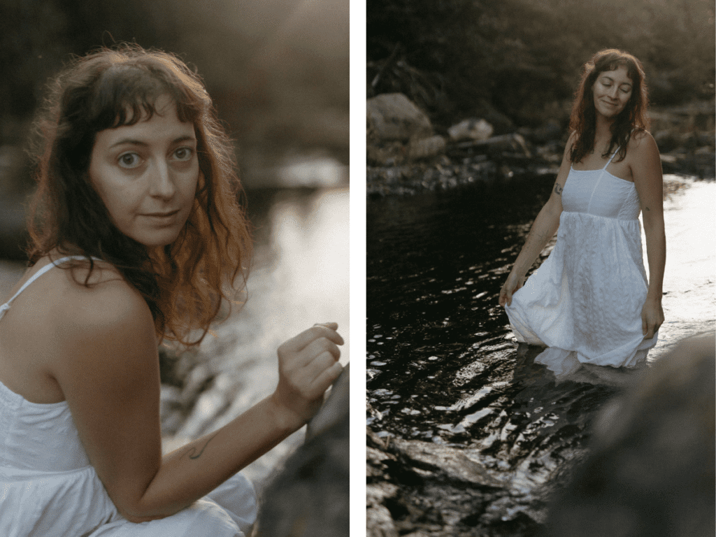 a woman in a long white dress wades through a river in evening light