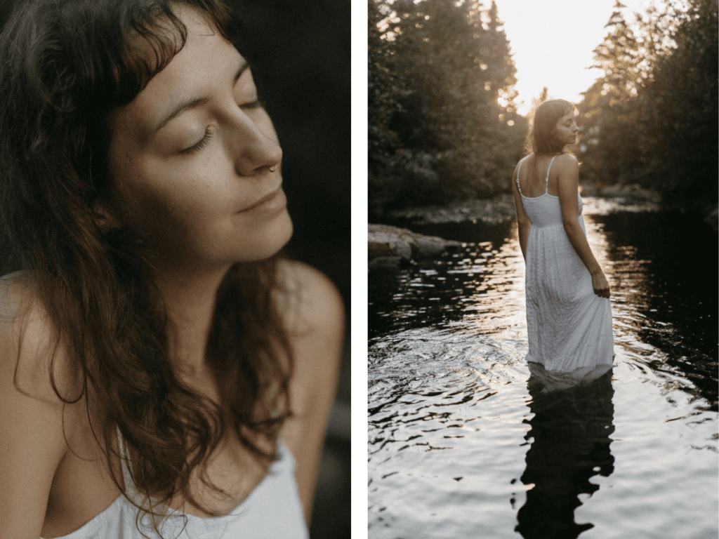 a woman in a long white dress wades through a river as the sun goes down