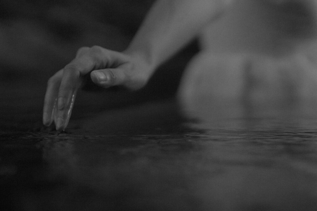 closely cropped photo of a woman's fingers dipping in a river