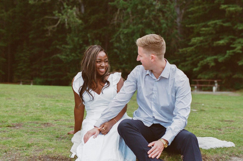 Bride laughs while groom holds her hand in a field in Banff