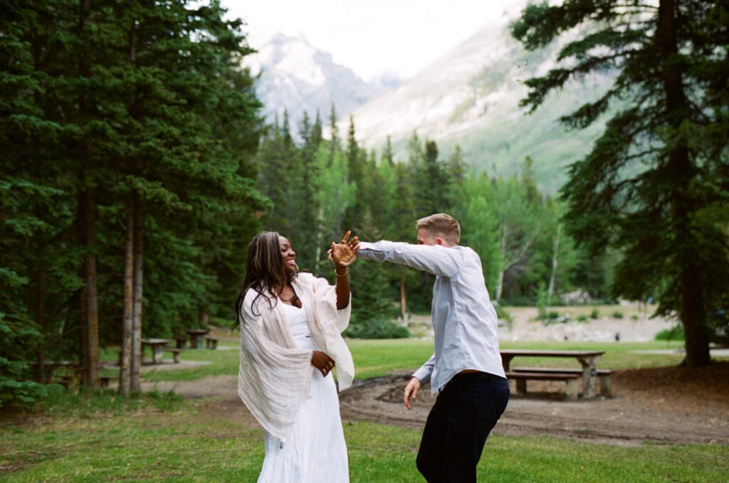 Bride and Groom laugh and spin each other around in a campground in Banff National Park