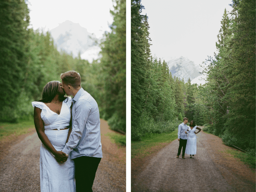 Bride and groom kiss on a dirt path surrounded by tall evergreen trees during their Banff elopement